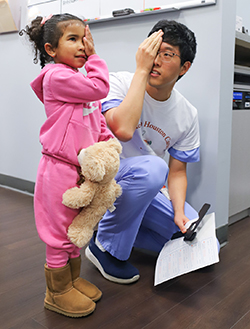 Eye care professional giving an eye exam to a young child