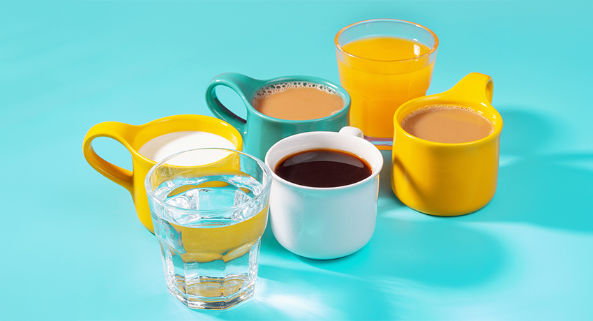 Multicolored mugs with drinks on a blue background side view.