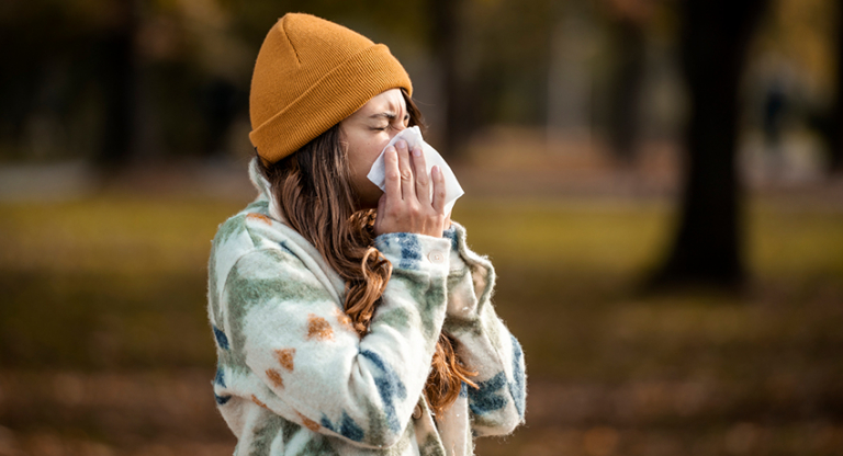 Woman sneezing in handkerchief at autumn