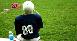 Football player sitting on a bench next to the field