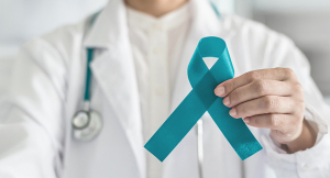 Teal awareness ribbon in doctor's hand, symbolic bow color for supporting patient with ovarian cancer