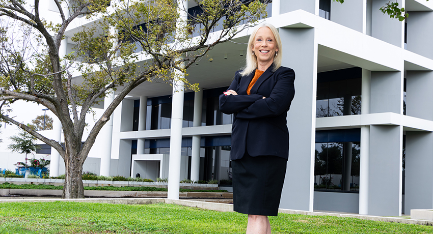 Kathy Hinze posing in front of UT Health Houston Bellaire Station