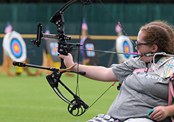 Natalia aiming her bow and arrow in an archery competition