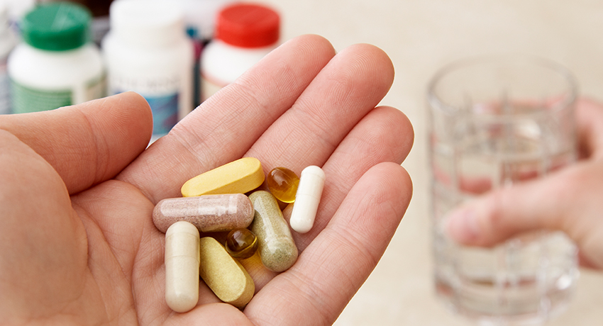 Health conscious person holding a variety of natural vitamins, supplements and herbal remedies