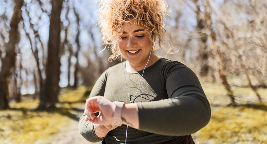 Young woman runner with headphones looking at smart